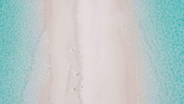 Aerial view showing narrow sandbar running through turquoise water and pristine white sand