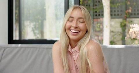 Relaxed Woman Smiling on Minimalist Grey Couch in Bright Living Room