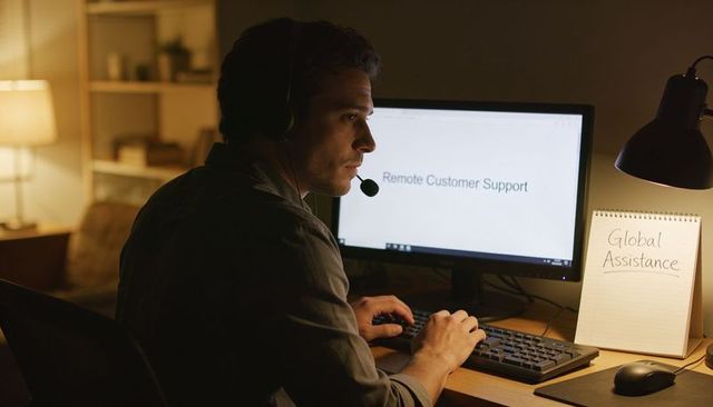 Late night remote customer support agent working from home with headset, keyboard and monitor