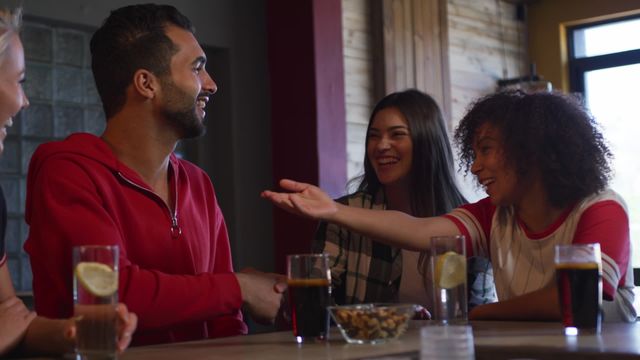 Group of diverse friends enjoying time together at bar, with one woman introducing a new friend to others. Great for representing friendship, fun, social gatherings, and multicultural interactions in a casual setting, perfect for advertising, lifestyle, and community-focused content.