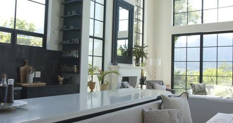 Sunlit Modern Open-Plan Kitchen Featuring Marble Island and Black-Framed Windows