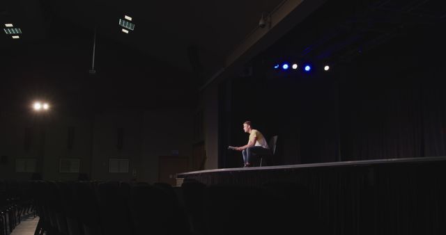 Performer Sitting Alone on Empty Theater Stage with Spotlight - Download Free Stock Images Pikwizard.com