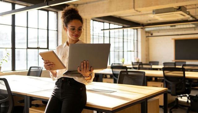 Young professional working on laptop and notebook in bright modern coworking loft