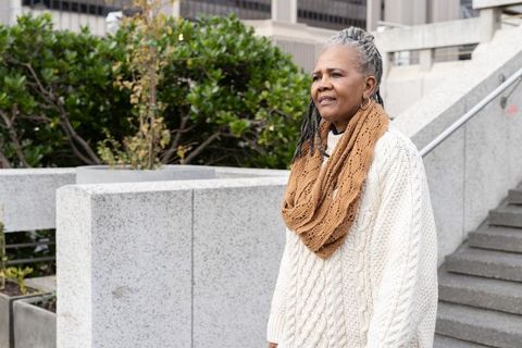 Senior african american woman standing in urban plaza wearing knit sweater and scarf