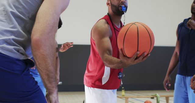 Basketball coach holding ball while giving instructions to players. Ideal for use in sports training guides, teamwork and leadership tutorials, and coaching blogs.