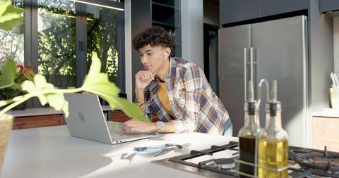 Man Working on Laptop in Modern Home Kitchen with Relaxed Concentration