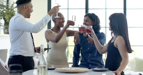 Friends celebrating at modern loft kitchen island toasting with champagne and cocktails
