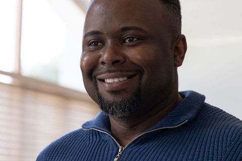 Smiling African American Man Close-Up Wearing Blue Zip Sweater Natural Light Headshot