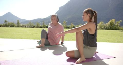 Asian Grandmother and Granddaughter Practicing Yoga Outdoors on a Bright Day
