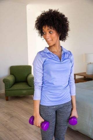 Woman exercising with dumbbells in cozy home interior setting