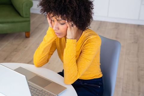African American Woman Stressed While Working on Laptop at Home