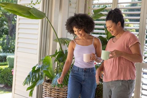 Women Enjoying Morning Coffee on Sunny Veranda with Greenery