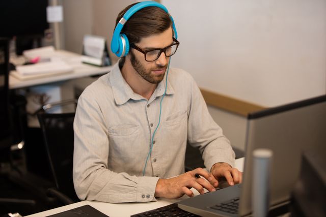 Businessman listening music through headphones while working - Download Free Stock Photos Pikwizard.com
