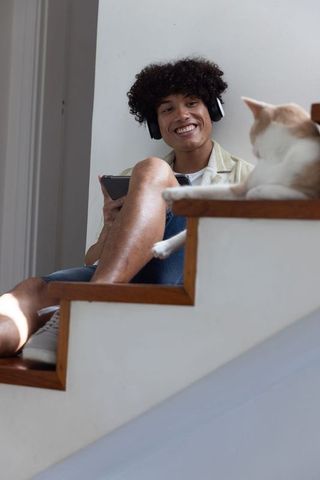 Young Man Enjoying Music on Staircase While Relaxing with Cat