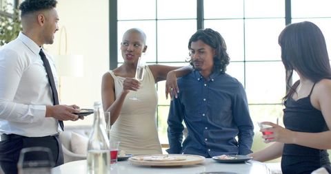Friends chatting and toasting at modern kitchen island during casual semi-formal gathering