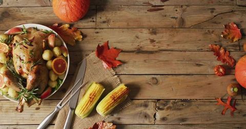 Rustic autumn harvest table with roast chicken, grilled corn, pumpkins and seasonal garnish