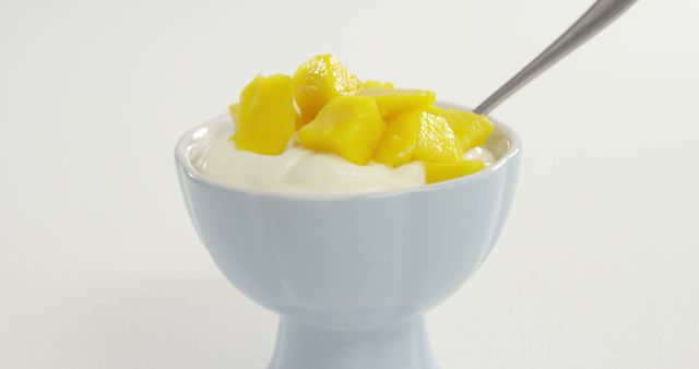 A bowl of creamy yogurt topped with diced mango offers a healthy snack option, with copy space. Its simplicity suggests a focus on nutritious and refreshing food choices.
