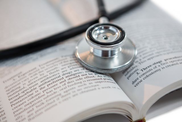 This image shows a stethoscope placed on an open medical book, symbolizing the intersection of healthcare and education. It is ideal for use in medical education materials, healthcare blogs, research articles, and academic presentations.