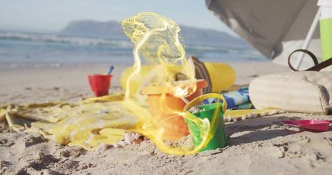 Colorful sand buckets on beach with sunny waves in background