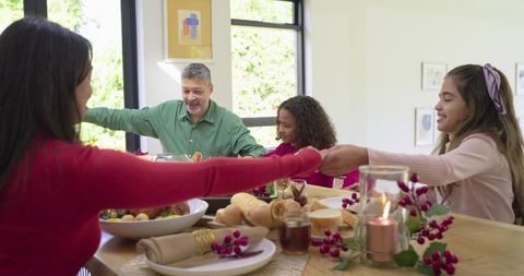 Multigenerational Family Holding Hands Around Festive Dining Table in Sunlit Home