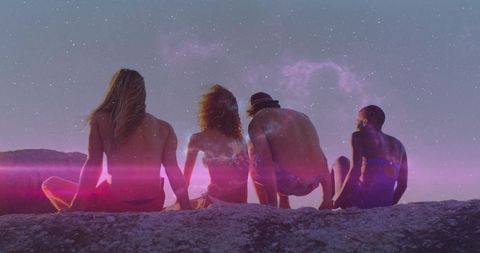 Friends Sitting on Cliff at Dusk with Starry Nebula Above