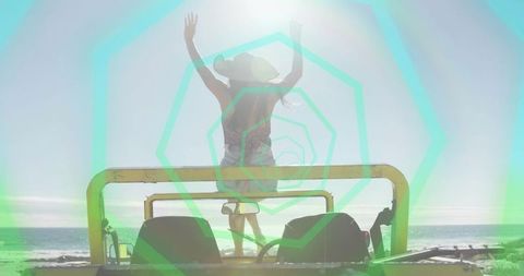 Woman standing on jeep raising arms facing ocean at beach sunset with geometric green overlay