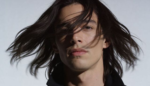 Windswept young male model with long hair portrait fashion headshot studio lighting