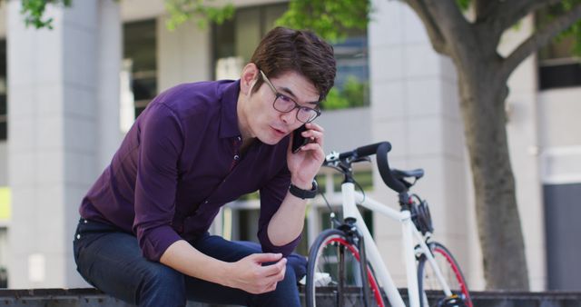 Asian man talking on smartphone while sitting near the corporate park. business and lifestyle concept