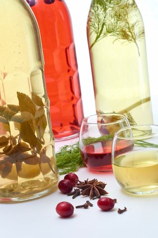 Colorful infused spirits and herbs on white background