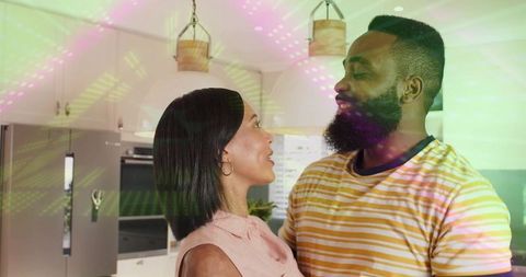 Couple sharing romantic moment in colorful modern kitchen with ambient pendant lights