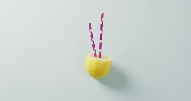 Halved lemon with straws sticking out, laying against white background. Ideal for creative beverage, refreshment, health, and summer concepts. Can be used in advertisements, websites, or magazines focused on drinks, fruit, or minimalist design.