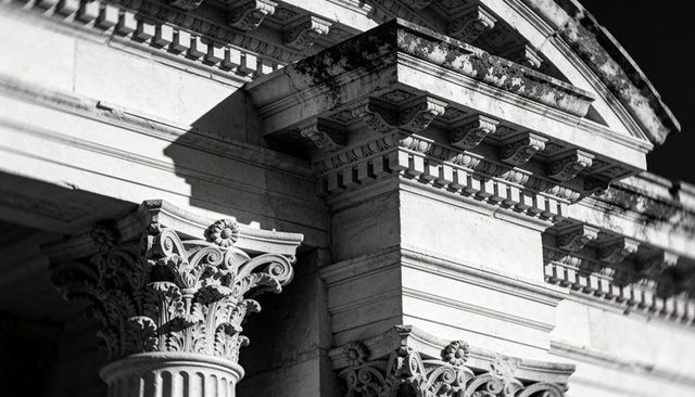 Corinthian column capitals and dentil molding on weathered marble classical facade