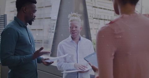 Multicultural team discussing project in modern atrium with man with albinism leading