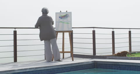 Senior Woman Painting by Poolside on Sunny Day