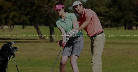 Male Golf Instructor Guiding Female Golfer Through Swing Mechanics on Sunlit Course
