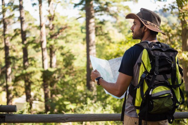 Man holding the map and looking at the distance in the forest