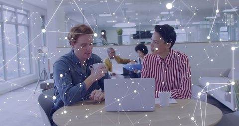 Colleagues collaborating over laptop and coffee in modern open office with network overlay