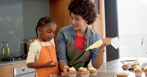 Mother and daughter bonding over cupcake decoration in cozy kitchen