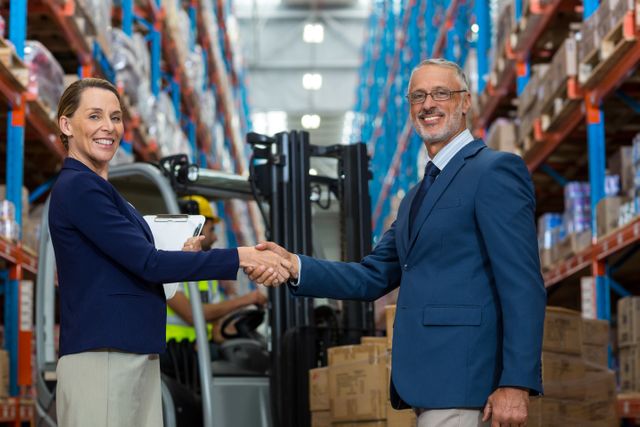 Warehouse manager shaking hands with client in warehouse