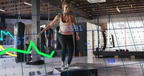 Woman exercising with plyometric box and fitness tracking in industrial gym