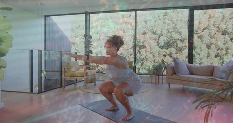 Woman performing bodyweight squat on yoga mat in sunlit modern living room