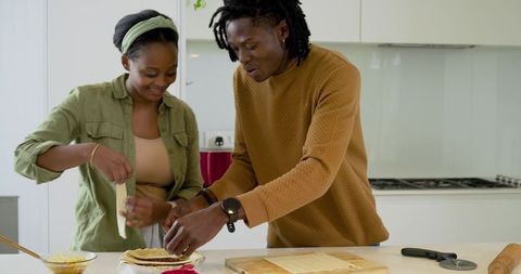 African American Couple Assembling Flatbreads on Kitchen Island Preparing Homemade Meal