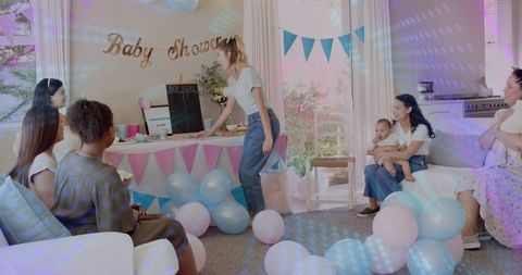 Pregnancy party host decorating gender reveal chalkboard at pastel baby shower