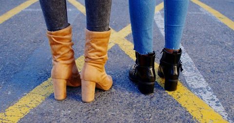 Stylish twin sisters displaying trendy footwear on city street