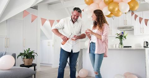 Happy couple celebrating engagement at home with wine
