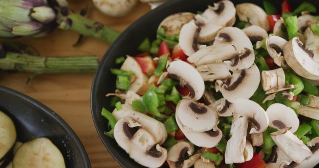 High angle close up of a bowl filled with mouth watering freshly chopped vegetables, with mushrooms, bread, a lemon and other ingredients standing on a wooden cooking table, in slow motion