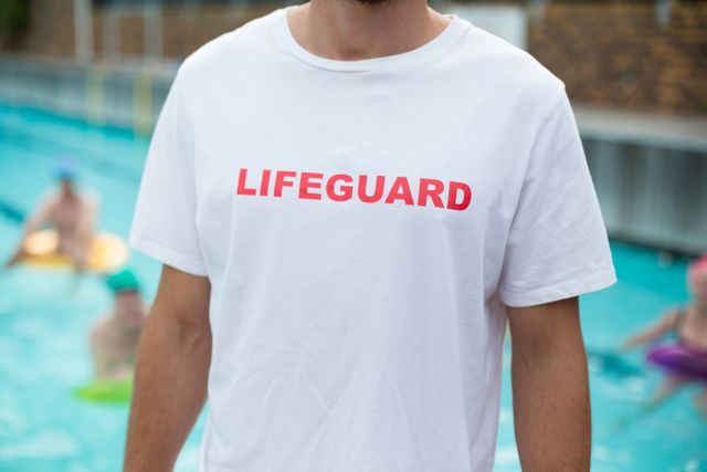 Mid section of male lifeguard standing at poolside