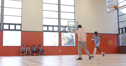 Basketball Team Training on Indoor Court with Coach