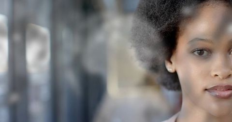 Young woman behind storefront glass with soft reflections and contemplative expression