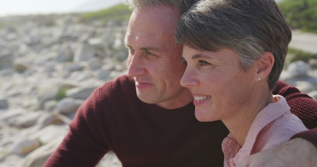 Couple enjoying time together at a rocky beach. Perfect for themes of love, togetherness, relationships, outdoor activities, mature couples, active lifestyle, and romantic getaways.